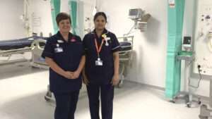 Two nurses in a new discharge lounge, with beds and medical equipment behind them.